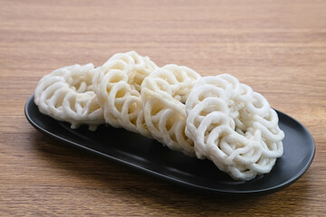 Krupuk or Kerupuk, Indonesia traditional crackers, served on black plate on wooden background.
