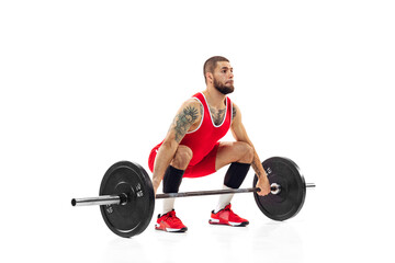 Fototapeta premium Full length portrait of man in red sportswear exercising with a weight isolated on white background. Sport, weightlifting, power, achievements concept
