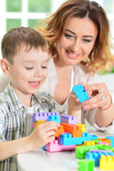 Woman and little boy playing with colorful plastic blocks together