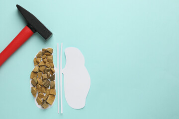 Paper cutout of kidneys with stones and hammer on turquoise background, flat lay. Space for text