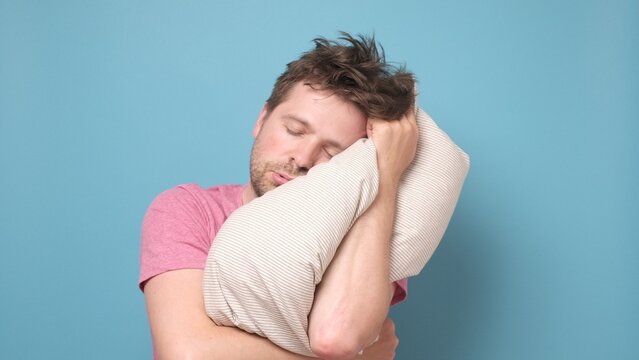 Caucasian man is tired and very sleepy keeping pillow on head.