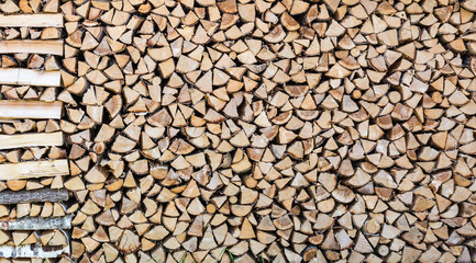 Close up of a patterned woodpile in front of a typical Swedish house