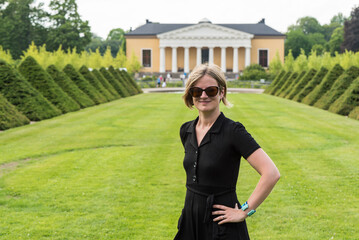 Cute thirty year old woman in black dress and sunglasses posing for the neo classical bontancal...