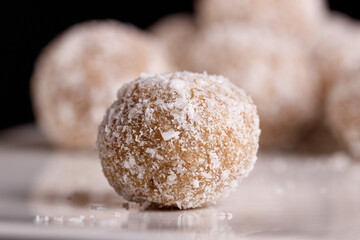 Beautiful sweets with coconut on a white plate on a black background