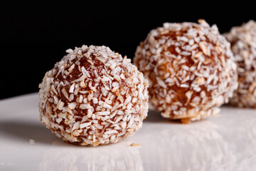 Beautiful sweets with coconut on a white plate on a black background