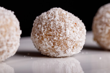 Beautiful sweets with coconut on a white plate on a black background