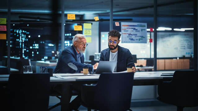Businesspeople in Modern Office: Business Meeting of Two Managers. CEO and Operations Director Talk, Discuss, Brainstorm Corporate Strategy, Implementing Marketing and Financial Plans. Evening Time.
