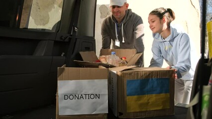 Volunteers putting the cardboard boxes with food and drink in the car trunk to deliver them to the ukranian refugees people.