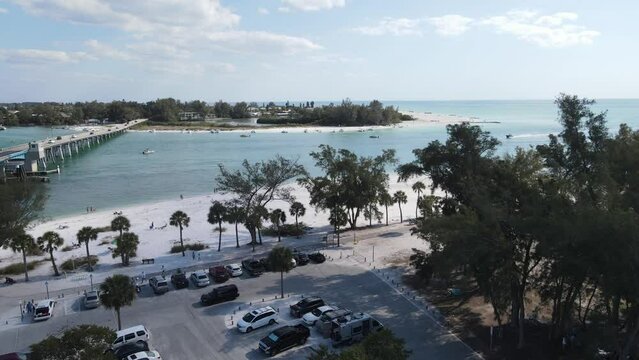 rising aerial looking south to Longboat Key in Sarasota, Florida.  Busy parking at Coquina Beach park