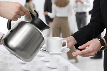 Waitress pouring hot drink during coffee break, closeup