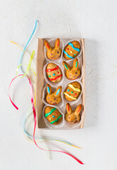 Easter cookies in the shape of eggs and rabbits, decorated with multicolored icing sugar, in a serving box. Light background. Top view