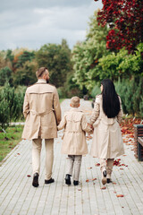 A happy family is walking in the park. Mom, dad and son are chatting and walking. A stylish family. parents in love.