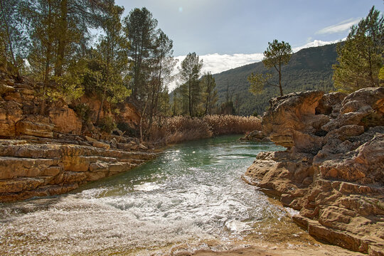 River flowing down in Cabriel Chorreras spot in Cuenca mountains  surrounded by rocky walls with pine trees on top of them