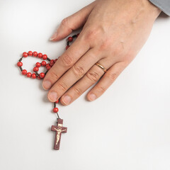 A woman holds a catholic holy rosary in her hand on a white background