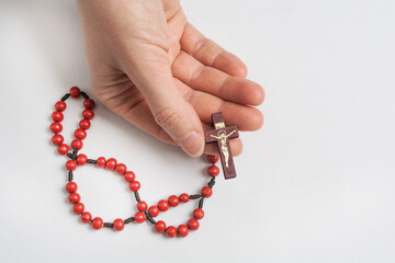 A woman holds a catholic holy rosary in her hand on a white background