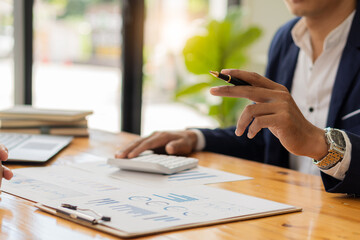 An accountant, businessman, or financial professional analyzes business report graphs and computational charts at the company's office. Banking business economy concept. and stock market research