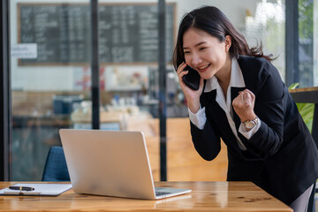 working concept Asian businesswoman using laptop Internet communication with customers at coffee shops Attractive woman sitting on laptop and smartphone in beverage restaurant