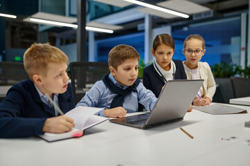 Children looking at laptop screen discussing something