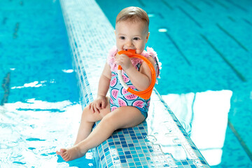 Fototapeta na wymiar Little girl is laughing in the pool at a swimming lesson.