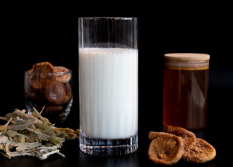 close up, set of medicine natural ingredients: milk, honey and dried fig on the black background