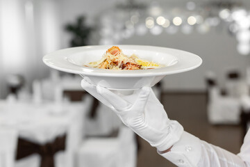 Close-up of a waiter serving a salad of fresh vegetables in a restaurant.