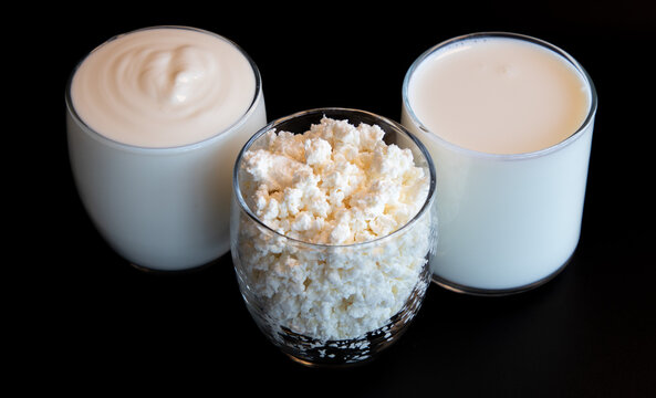 close up milk products in glasses from the top view on the black background, milk, cottage, soure cream or yogurt