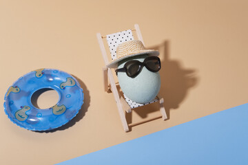 Naklejka premium A cheerful Easter composition with an egg in sunglasses lies on a sun lounger on the beach