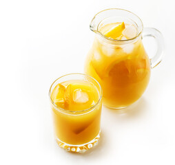 Pitcher and glass of tasty cold juice from grapefruit or orange, refreshing drink with ice isolated on white background. Refreshing summer drinks, selective focus.