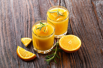 Two glasses with gin with grapefruit or orange and rosemary, refreshing drink with ice on wooden...