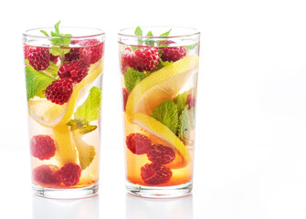 Detox fruits water with ice, raspberries, lemon, mint on wooden background. Refreshing summer cocktail, summer drinks.