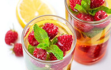 Detox fruits water with ice, raspberries, lemon, mint isolated on white background . Refreshing summer drinks, top view, close up