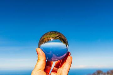 Paisaje con mar y nubes reflejado en una lensball
