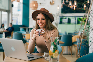 woman drinking coffee and using laptop computer in cafe