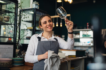 waitress cleaning wine glass in restaurant - Powered by Adobe