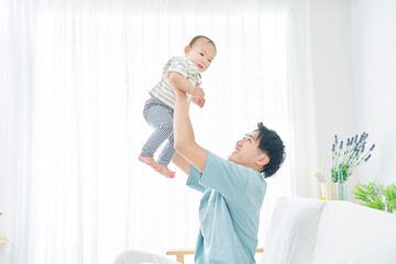 Fototapeta premium 赤ちゃんを抱き上げる父親 リビング