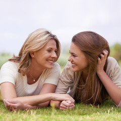 Special time with her daughter. A loving mother and daughter lying side by side on the grass. - obrazy, fototapety, plakaty