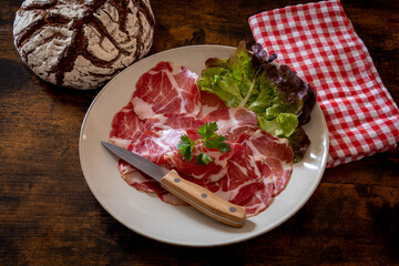 dish of coppa with a ball of bread on a wooden table