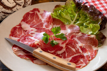 dish of coppa with a ball of bread on a wooden table