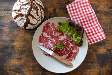 dish of coppa with a ball of bread on a wooden table