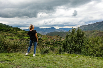 Naklejka premium A girl on the background of the village of Kurib in the Caucasus mountains, on top of a cliff. Dagestan Russia June 2021
