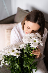 Good looking Caucasian woman smells flowers, she is happy for get a fresh bouquet of white chrysanthemum