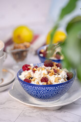 Blue bowl of cottage cheese with berries, honey and nuts for breakfast, selective focus.