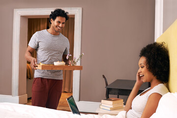 Surprising her with breakfast. A young man bringing his girlfriend breakfast in bed.