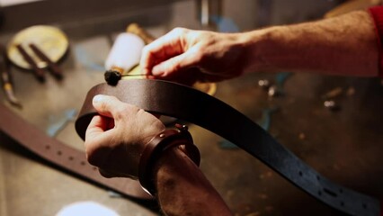 A man paints edges of a blank for a leather belt