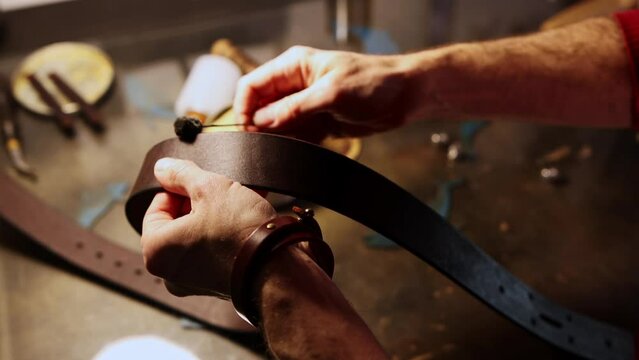 A man paints edges of a blank for a leather belt