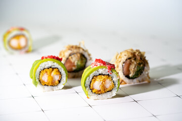 Set of sushi roll with shrimp, avocado and flying fish caviar on white table. Creative image with...