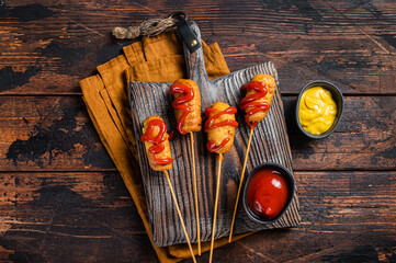 Mini Deep fried corn dogs with mustard and ketchup on wooden board. Wooden background. Top view