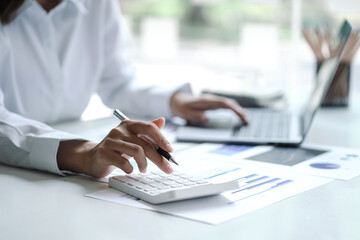 Business Asian woman using calculator for do math finance on wooden desk in office and business...