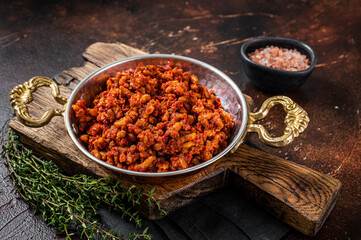 Hot ground beef stewed with tomato sauce and spices in a skillet with spices.  Dark background. Top view