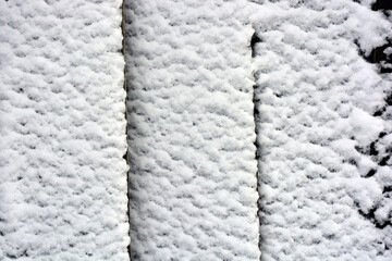 White, fluffy snow glued to a dark metal sheet, winter white background. 